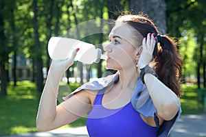 Young sporty girl drinking water from a bottle