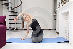 Young sporty girl playing sports at home on yoga mat. Active Lifestyle. Doing Fitness At Home. Holiday Leisure. Body Balance.