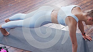 Young and sporty girl in sportswear doing exercises at home. Fit and slender blond woman goes in for sports and fitness