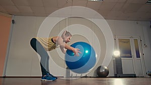 Young Sporty Lady is Exercising alone with Fitball at Hands in Training Gym