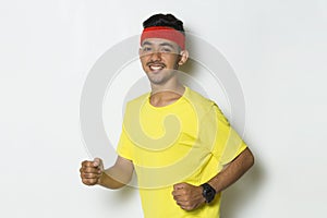 Young sporty man dressed in yellow tshirt running on white background