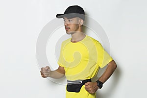 Young sporty man dressed in yellow tshirt running on white background