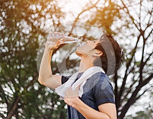 Young sporty man drinking water in park