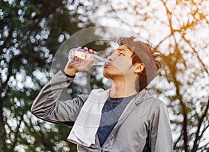 Young sporty man drinking water in park