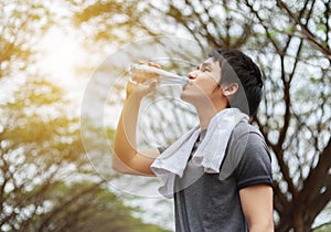 Young sporty man drinking water in park