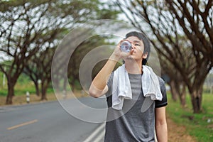 Young sporty man drinking water in park