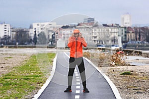Young sporty man in orange windbreaker jacket jogging on a cloudy day