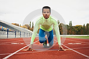 Young sporty man are ready to run on racetrack. Fit well formed people at large nice modern stadium