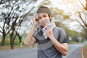 Young sporty man resting and wiping his sweat with a towel after