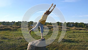 Young sporty man standing at stone at yoga pose outdoor. Yogi practicing yoga moves and positions in nature. Athlete
