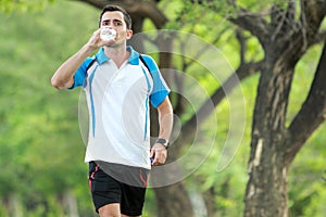 Young sporty man walking while drinking a mineral water