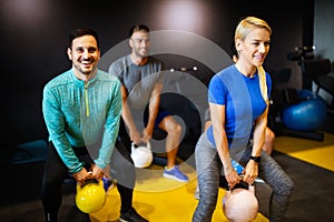 Young sporty people working out together with kettle bells in a gym.