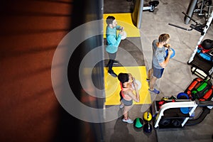 Young sporty people working out together with kettle bells in a gym.