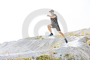 Young sporty runner man jumping from hill on cross