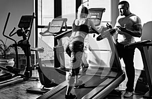 Young sporty sexy couple workout cardio exercise gym. Sportive couple in gym. Personal trainer helping woman doing