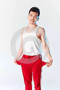 Young sporty stylish male dancer in red sweatpants posing isolated in studio