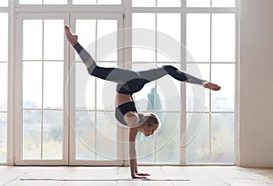 Young sporty woman balancing on hands with splitted legs