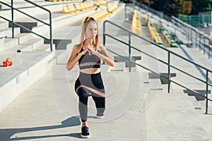 Young sporty woman doing exercises with rubber band outdoor