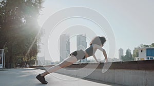 Young sporty woman doing push-up exercise on the city beach