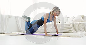 Young sporty woman is doing push-ups exersice from knees at home, side view.
