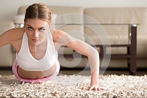 Young sporty woman doing push ups, plank exercise at home