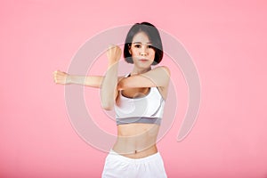 Young sporty woman doing shoulder and arm stretching isolated on pink background