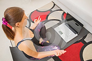 Young sporty woman is doing training  yoga ion line with modern laptop screen
