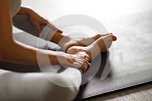 Young sporty woman doing yoga stretching exercise sitting in gym near bright windows