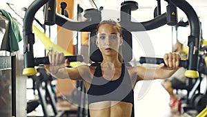 Young sporty woman exercising on a pec deck machine