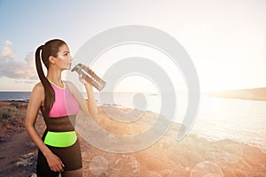 Young sporty woman jogger drinking water from bottle
