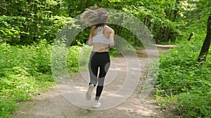 Young sporty woman jogging through the forest