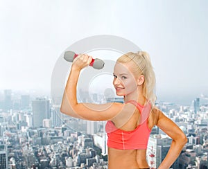 Young sporty woman with light dumbbell
