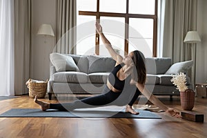 Young sporty woman performs Side Lunge asana at home