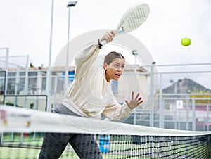 Young sporty woman playing paddle tennis outdoors