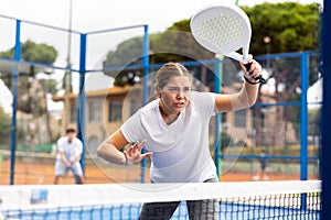 Young sporty woman playing paddle tennis outdoors