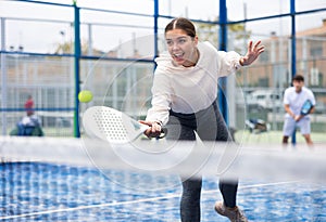 Young sporty woman playing paddle tennis outdoors