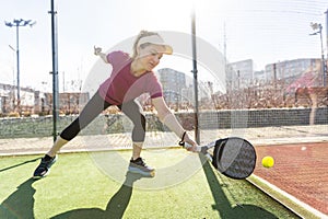 Young sporty woman playing padel game in court on sunny day