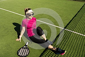 Young sporty woman playing padel game in court on sunny day