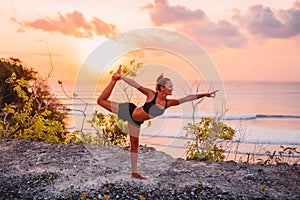 Young sporty woman practicing yoga at bright sunset time