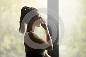 Young sporty woman doing Alternate Nostril Breathing photo