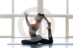 Young sporty woman practicing yoga, doing Eka Pada Rajakapotasan