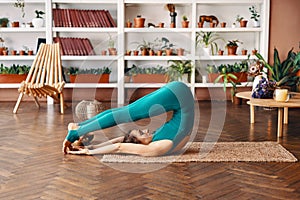 Young sporty woman practicing yoga at home doing exercise Halasana Plow Pose photo