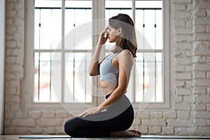 Young sporty woman practicing yoga, nadi shodhana pranayama pose