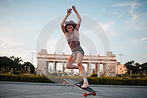 Young sporty woman riding on the longboard in the park.