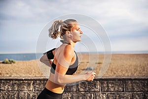 Young sporty woman runner running outside on a beach in nature.