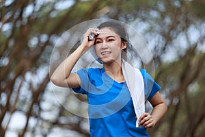 Young sporty woman running and wiping her sweat with a towel in