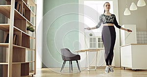 Young sporty woman is skipping rope making cardio training at home in kitchen.