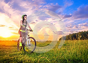 Young sporty woman at sunset on a bicycle. Sporty girl on bike stopped to enjoy the moment at beautiful sunset. Lens