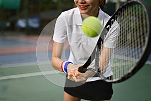 Young sporty woman tennis player hitting ball with a racket during match. Fitness, sport, exercise concept