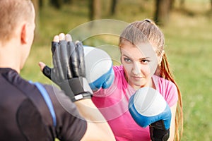 Young sporty woman training boxing with trainer